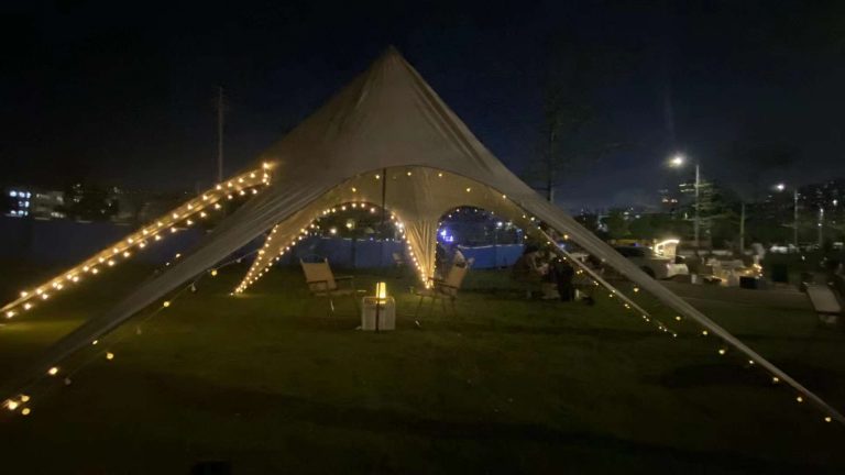 White star canopy illuminated with string lights at an evening outdoor event